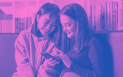 Two young women smiling with a phone